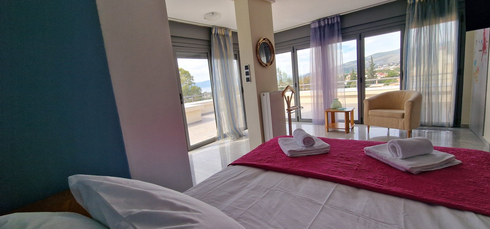 Εσωτερικό υπνοδωματίου με διπλό κρεβάτι, καθιστικό και μεγάλες τζαμαρίες στη Villa Memories