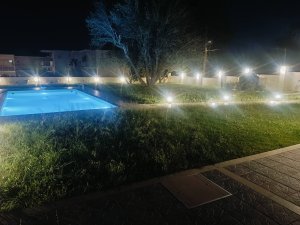 Βραδινή λήψη του κήπου της Villa Memories με εντυπωσιακό φωτισμό στα δέντρα και την πισίνα