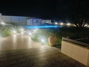 Φωτισμένη πισίνα το βράδυ στη Villa Memories με το εξωτερικό pool bar στο βάθος