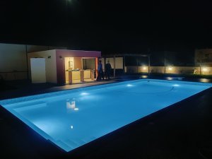 Μεγάλη ιδιωτική πισίνα της Villa Memories στην Κινέτα φωτισμένη τη νύχτα με χώρο χαλάρωσης