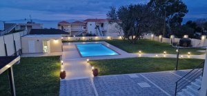 Εξωτερικός χώρος της Villa Memories στην Κινέτα με πισίνα, φωτισμένα μονοπάτια και μεγάλο κήπο