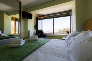 Υπνοδωμάτιο της Villa Memories στην Κινέτα με διπλό κρεβάτι, πολυθρόνα και θέα από το παράθυρο