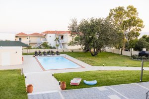 Ιδιωτική πισίνα της Villa Memories με ξαπλώστρες και δέντρα στον κήπο