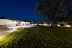 Φωτισμένη πισίνα και καταπράσινος κήπος της Villa Memories στην Κινέτα τη νύχτα