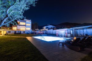 Ξαπλώστρες δίπλα στην πισίνα της Villa Memories με φωτισμό τη νύχτα