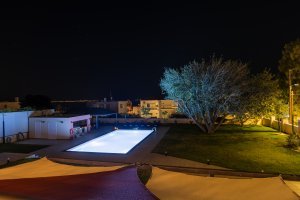 Φωτισμένος κήπος και πισίνα της Villa Memories στην Κινέτα κατά τη νύχτα