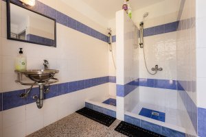 Μπάνιο της Villa Memories με δύο ντους, νιπτήρα και λευκά-μπλε πλακάκια