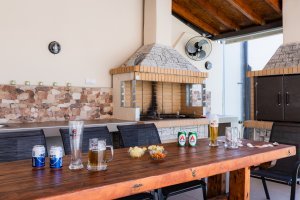 Εξωτερική τραπεζαρία BBQ στη Villa Memories με ξύλινο τραπέζι, ποτά και ψησταριά