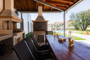 Ξύλινο τραπέζι BBQ στη Villa Memories με θέα την πισίνα και τον κήπο