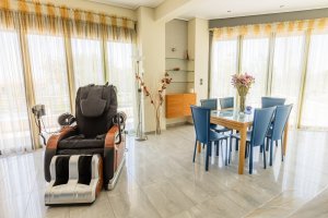 Ενιαίος χώρος σαλονιού και τραπεζαρίας στη Villa Memories με πολυθρόνα μασάζ και μεγάλα παράθυρα