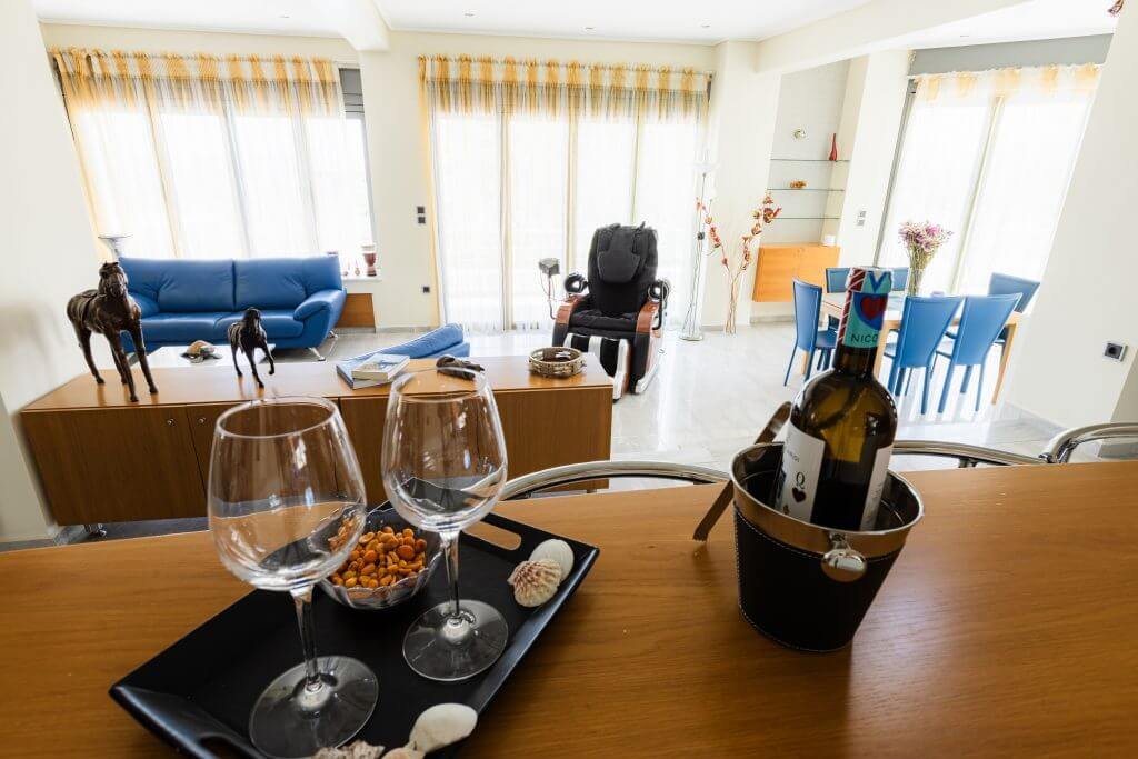 Εσωτερικός χώρος καθιστικού και τραπεζαρίας στη Villa Memories στην Κινέτα με καναπέδες και τραπέζι φαγητού