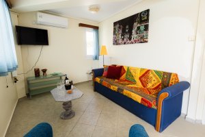 Σαλόνι της Villa Memories με μπλε καναπέ, τραπεζάκι και τηλεόραση τοίχου