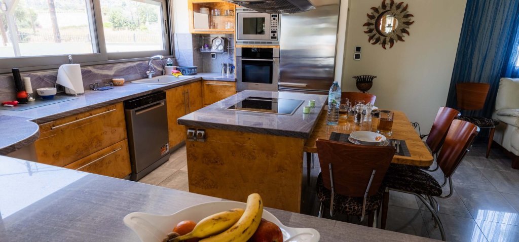 Ευρύχωρη κουζίνα με νησίδα, εντοιχισμένες συσκευές, πλυντήριο πιάτων και τραπεζαρία στη Villa Memories