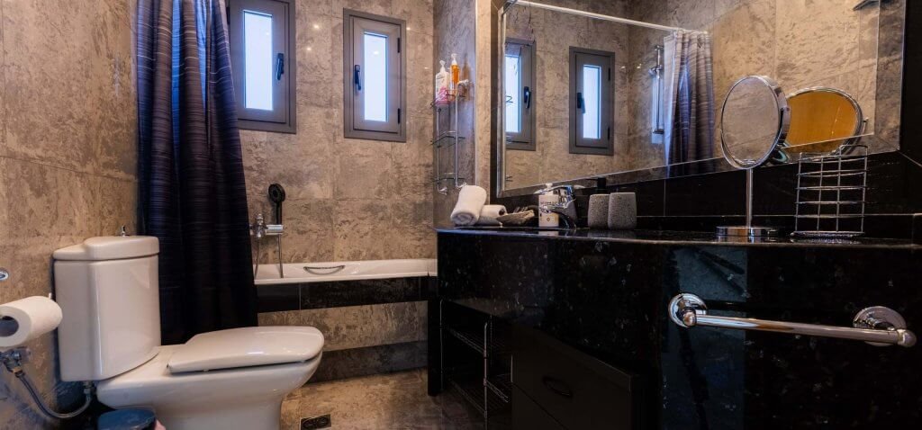 Μπάνιο υψηλής αισθητικής στη Villa Memories με μαύρο μάρμαρο, μπανιέρα και γκρι πλακάκια